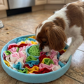 Dog playing with a colorful puzzle toy on a kitchen floor.