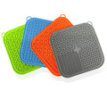 Four silicone trivets in green, blue, orange, and gray on a white background